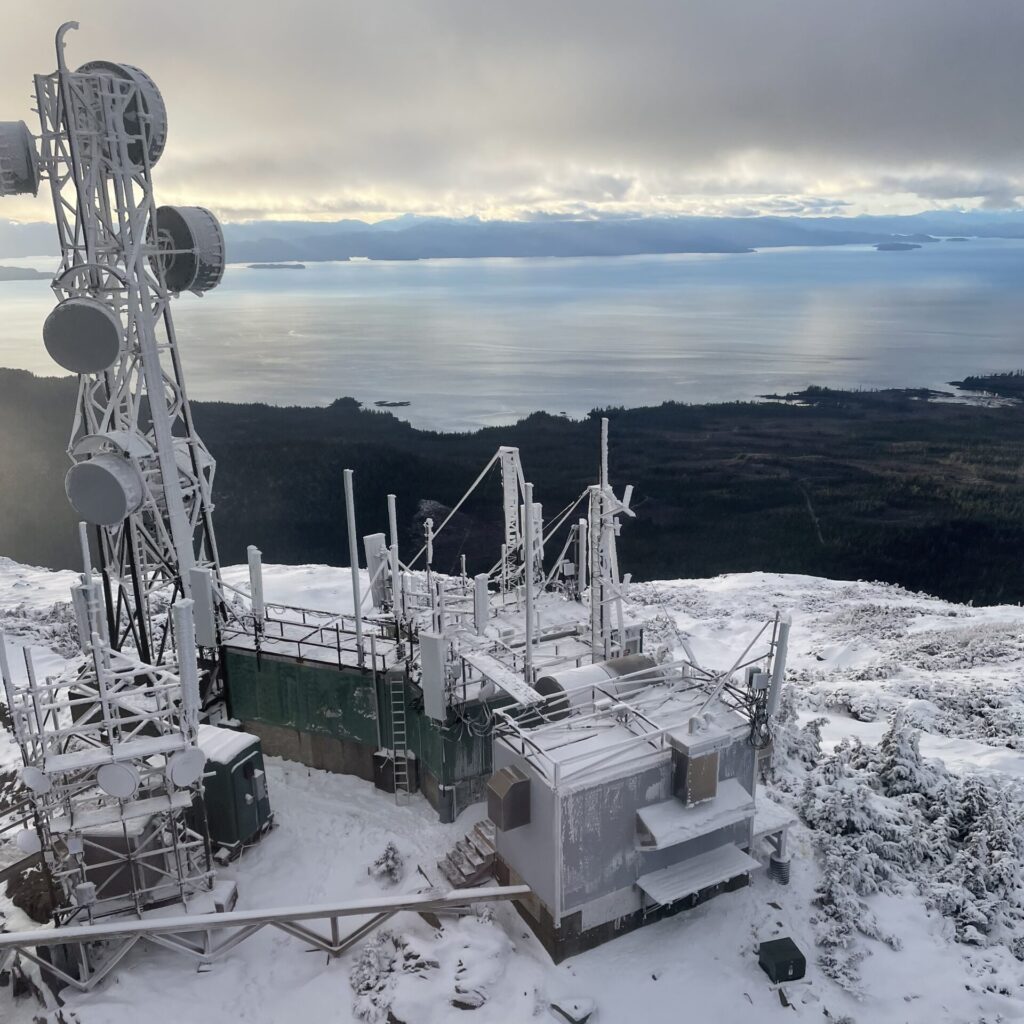 Telecommunication infrastructure atop a snowy mountain.